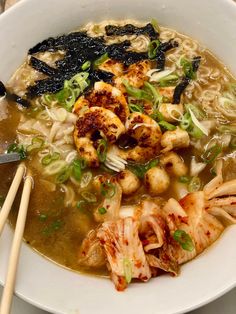 a white bowl filled with noodles and shrimp next to chopsticks on a table