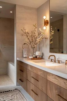 a bathroom with two sinks, mirrors and a large mirror above the sink is a vase with flowers