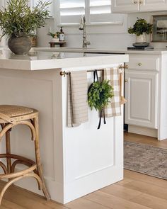 a kitchen island with towels hanging on it's hooks and two potted plants