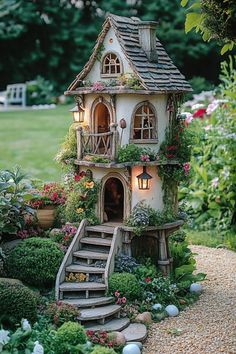 a fairy house with stairs and lights in the middle of a flower garden, surrounded by greenery