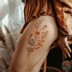 a close up of a person's thigh with flowers tattooed on the side and behind her