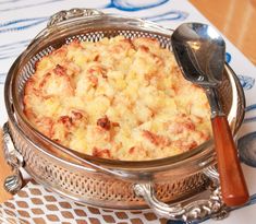 a casserole dish on a silver platter with a wooden spoon