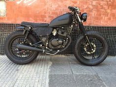 a black motorcycle parked next to a brick wall