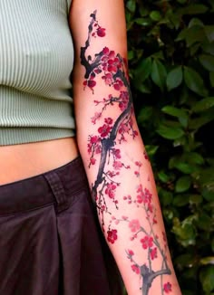 a woman's arm with flowers on it and a tree branch in the background