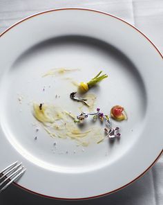 a white plate topped with a piece of food next to a knife and fork on top of a table