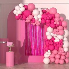 pink and white balloons are hanging from the ceiling