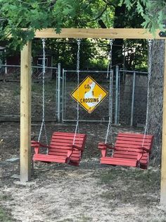 two red chairs sitting on top of a wooden swing set next to a sign that says go crossing