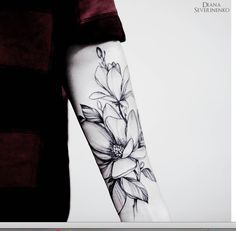 a black and white photo of a woman's arm with flowers tattooed on it