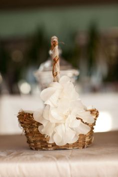 a basket filled with white flowers sitting on top of a table next to a candle