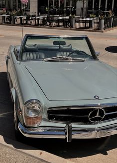 an old mercedes sits parked on the side of the road