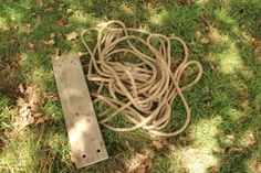 a piece of wood sitting on top of grass next to a roped device in the ground