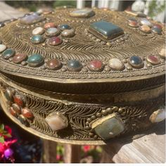 an ornately decorated box sitting on top of a wooden table next to some flowers