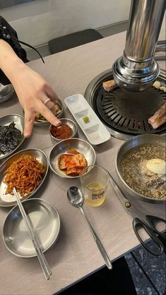 a table topped with bowls filled with food next to an open fire place heater