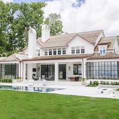 a large white house sitting on top of a lush green field next to a swimming pool