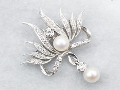 This luxurious brooch or pendant draws the eye with diamonds and pearls, perfectly combining opulence and classic style. The sparkling stones are securely set in the white gold, creating an elegant and timeless piece.*Please note, one of the diamonds is chipped and the piece has been priced accordingly.Metal: 14K White GoldGem: 2 PearlsGem Measurements: 7.5 mm, RoundAccents: 44 Single Cut Diamonds totaling .90 Carats, VVS-SI in Clarity, H-J in ColorMeasurements: 41 x 45 mm Brooch Diamond, Art Deco Brooch, Antique Brooches, Wedding Pins, Diamond Brooch, Gold Brooches, Pearl Brooch, Brooches Handmade, Diamond Art