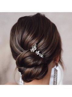 the back of a woman's head with hair combs in her hair and earrings