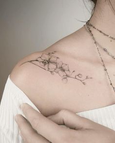 a woman's chest with a flower tattoo on her left shoulder and the other arm