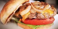 a cheeseburger with onions, tomato and lettuce on a white plate