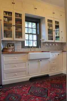 a kitchen with white cabinets and red rug