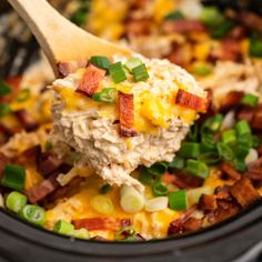 a wooden spoon is scooping some food out of the crock pot with bacon and green onions