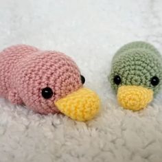 two small crocheted stuffed animals laying on top of a white blanket next to each other