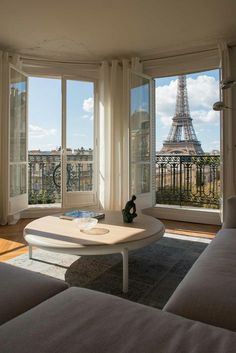 a living room with two couches and a coffee table in front of the eiffel tower