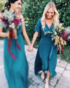 two women in dresses holding hands and walking