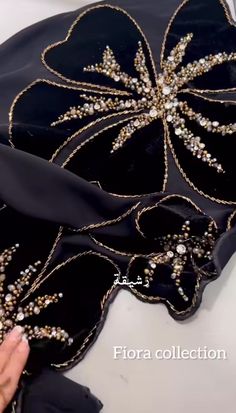 a woman's hand is touching the back of a black dress with gold sequins on it