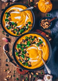 two bowls of carrot soup with cashews and parsley on the side, surrounded by pumpkins