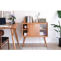 a wooden desk with a laptop on top of it next to a potted plant