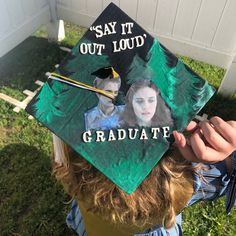 a child wearing a graduation cap with the words say it out loud and graduate on it