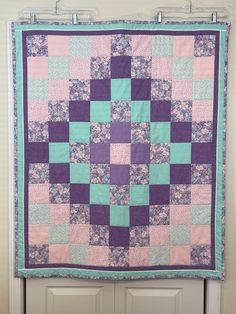 a purple and blue quilt hanging on a door