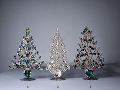 three small christmas trees in different colors and sizes, each decorated with swaro - cut crystals