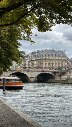 a boat floating down a river next to a bridge