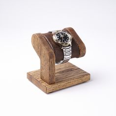 a wooden stand with a watch on it and a leather band around the wrist strap