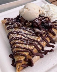 a white plate topped with chocolate crepe and ice cream on top of it