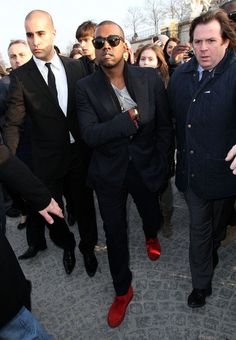 two men in suits and red shoes are surrounded by people