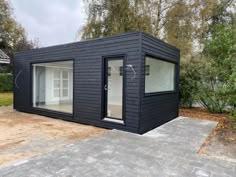 a small black building sitting in the middle of a yard