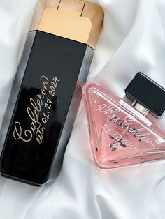 two perfume bottles sitting next to each other on a bed