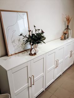 a vase with flowers sitting on top of a white cabinet