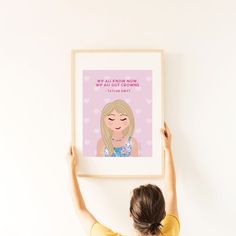 a woman is holding up a framed poster