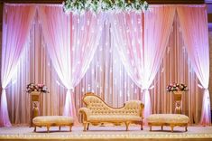 an elegant stage set up with pink drapes and white flowers on the headboard