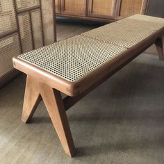 a wooden bench sitting on top of a hard wood floor next to drawers and cabinets