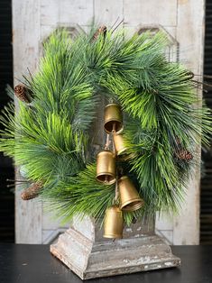 a wreath with bells and pine cones is on a table next to an old door