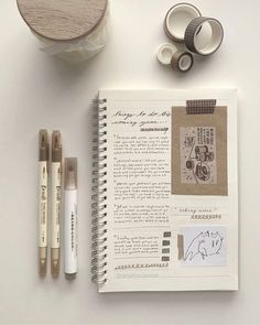 an open notebook with some paper and markers next to two rolls of washi tape