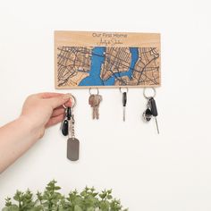 a wooden key holder with four keys hanging from it's sides and a map on the wall