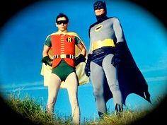 two men dressed as batman and robin wayne standing next to each other in the grass