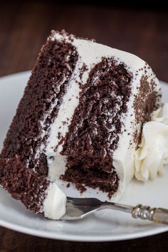 a slice of chocolate cake with white frosting on a plate