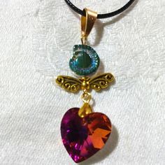 This Is A Shimmery Golden Angel With Golden Wings, A Pink Titanium Coated Heart Rhinestone, And A Blue Glass Shell Bead For The Top. The Colors Really Shimmer And Shine With This Piece! I Love The Bright Pink With The Iridescent Blues Of The Shell And The Gold Compliments It All. The Pendant Measures Approximately 2 1/4"X 3/4". It Comes With A Black Corded Necklace With An Extension. I Hope You Like It And Thanks For Stopping By. Feel Free To Leave Me A Fair Offer. :) Heart-shaped Beaded Crystal Necklace For Gift, Pink Heart Pendant Necklace For Jewelry Making, Pink Beaded Heart Pendant Jewelry, Pink Crystal Necklaces For Valentine's Day, Pink Crystal Necklace For Valentine's Day Jewelry Making, Handmade Pink Heart Crystal Necklaces, Heart-shaped Crystal Beaded Jewelry, Pink Pendant Necklace, Golden Angel