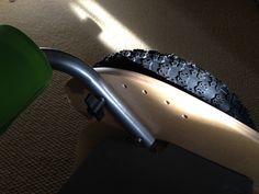 a close up of a bike tire with a green wheelbarrow behind it on the floor